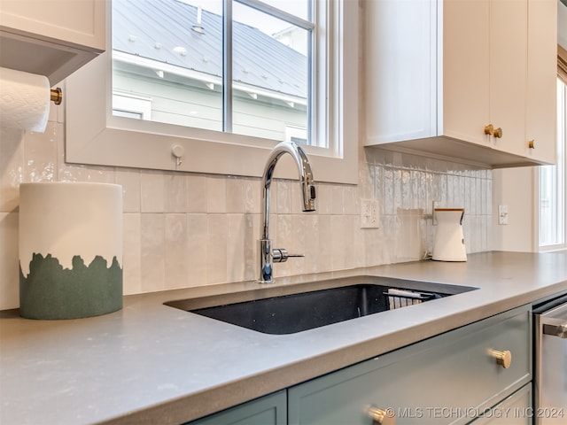 kitchen featuring backsplash, sink, and white cabinets