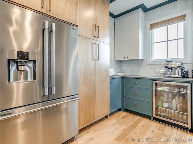 kitchen featuring stainless steel fridge, beverage cooler, light hardwood / wood-style flooring, backsplash, and light brown cabinetry