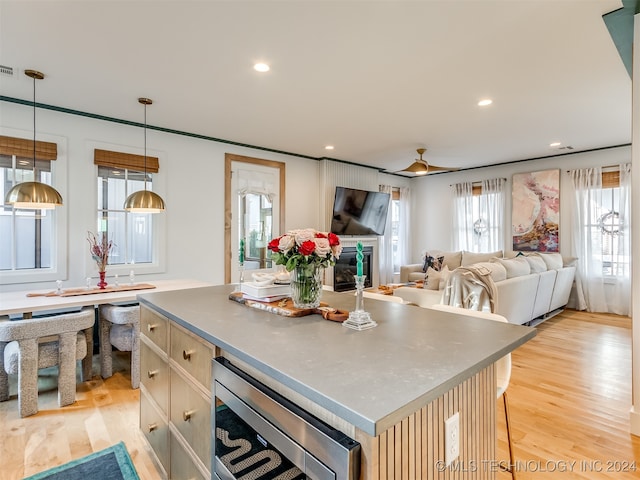 kitchen featuring light wood-type flooring, hanging light fixtures, a breakfast bar area, and a center island