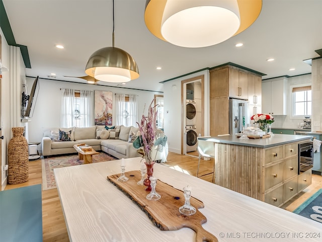 dining room featuring light hardwood / wood-style floors, a healthy amount of sunlight, and stacked washer and clothes dryer