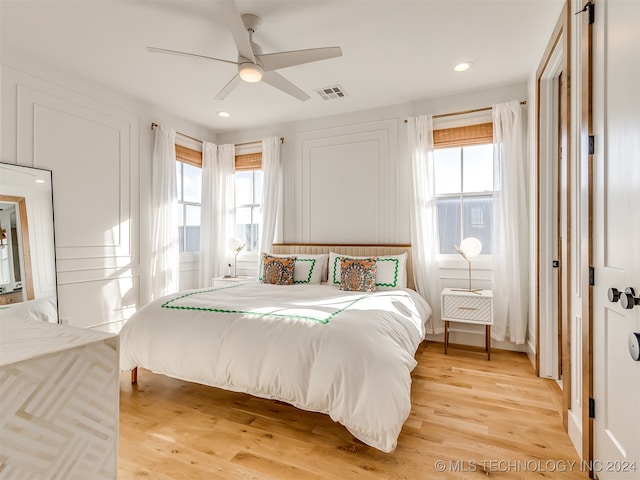 bedroom with ceiling fan, light hardwood / wood-style floors, and multiple windows