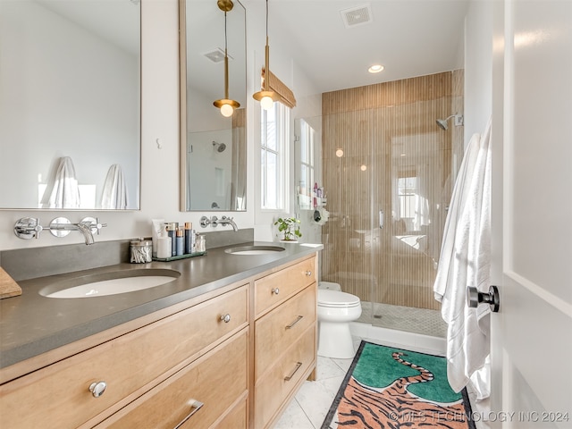 bathroom with vanity, tile patterned flooring, toilet, and tiled shower