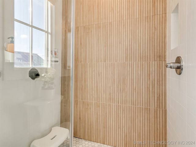 bathroom with a tile shower and toilet