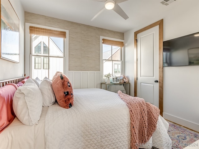 bedroom with multiple windows, wood-type flooring, and ceiling fan