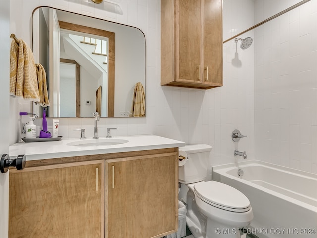 full bathroom with tiled shower / bath, vanity, tasteful backsplash, tile walls, and toilet