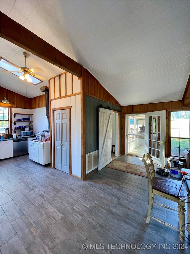 kitchen featuring wood-type flooring, wood walls, vaulted ceiling with beams, and a wealth of natural light