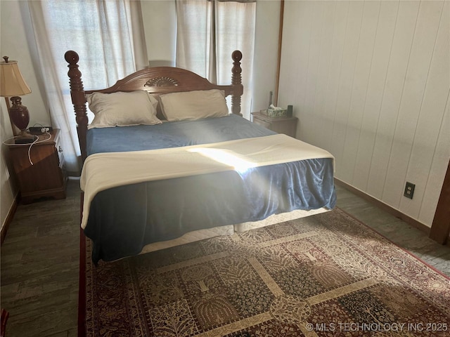 bedroom featuring dark wood-type flooring and wood walls