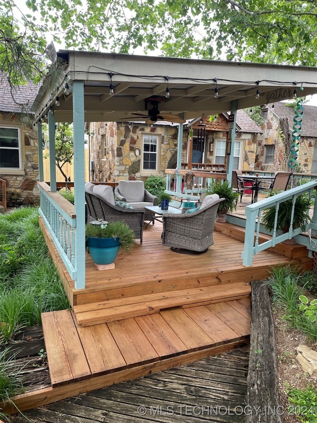 wooden terrace with ceiling fan and an outdoor living space