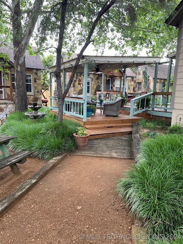 rear view of property featuring ceiling fan and a deck