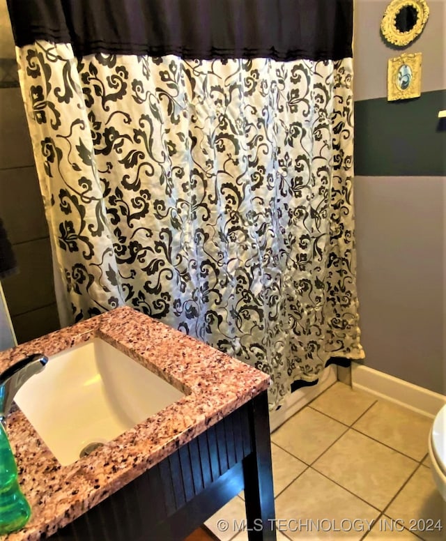 bathroom with a shower with curtain, toilet, sink, and tile patterned flooring