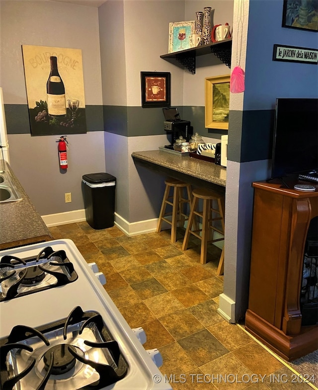 kitchen with a breakfast bar, sink, and gas range gas stove