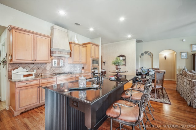 kitchen featuring light brown cabinetry, custom exhaust hood, and light hardwood / wood-style flooring