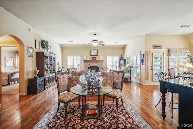 dining space featuring ceiling fan, a fireplace, and hardwood / wood-style floors