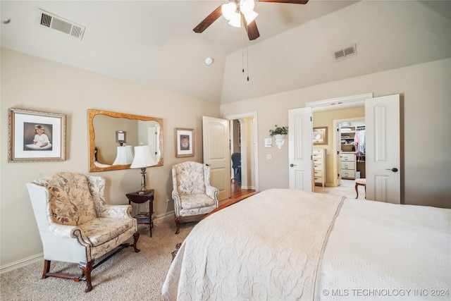 bedroom featuring lofted ceiling, a walk in closet, ceiling fan, and light colored carpet