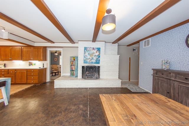 unfurnished living room with a fireplace, ceiling fan, and beamed ceiling