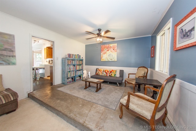 living area with concrete flooring, ceiling fan, and crown molding