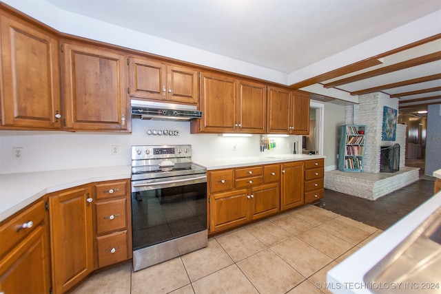 kitchen featuring ventilation hood, beam ceiling, a fireplace, light tile patterned floors, and stainless steel electric range