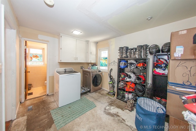 laundry area with separate washer and dryer and cabinets