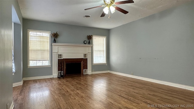 unfurnished living room with visible vents, a fireplace, baseboards, and wood finished floors