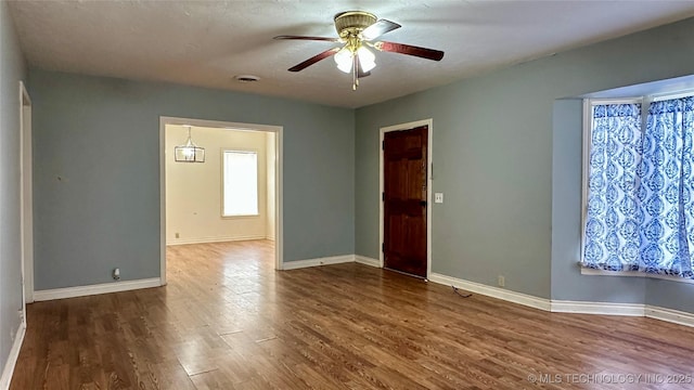 unfurnished room with visible vents, wood finished floors, a ceiling fan, and baseboards