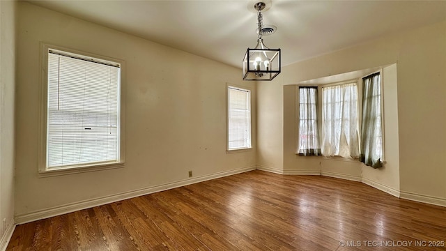 empty room featuring visible vents, baseboards, and wood finished floors