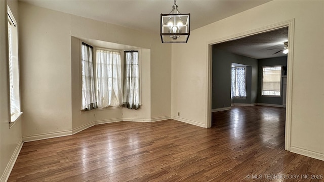 interior space with ceiling fan with notable chandelier, wood finished floors, and baseboards