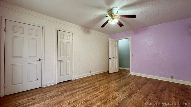 unfurnished bedroom with a textured wall, a textured ceiling, baseboards, and wood finished floors