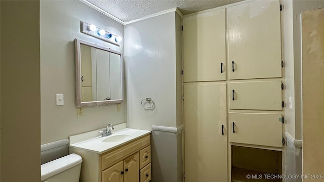 bathroom with a textured ceiling, vanity, and toilet