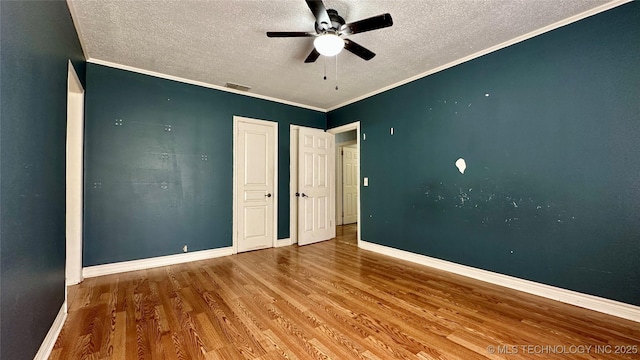 unfurnished bedroom with baseboards, wood finished floors, and crown molding