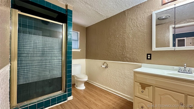 full bathroom with a textured wall, toilet, a stall shower, a textured ceiling, and wood finished floors