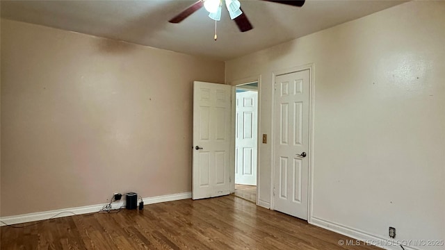 empty room with ceiling fan, wood finished floors, and baseboards