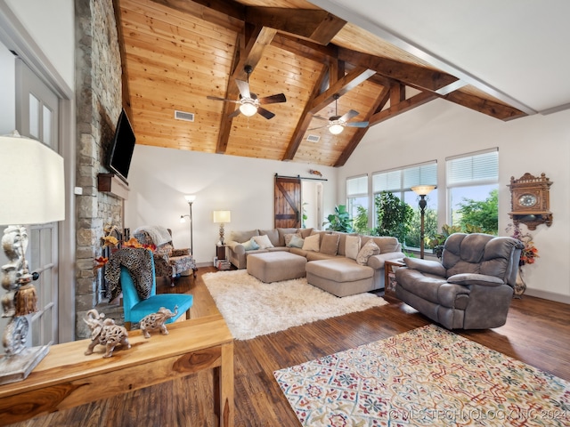 living room featuring beam ceiling, hardwood / wood-style flooring, a fireplace, and a barn door