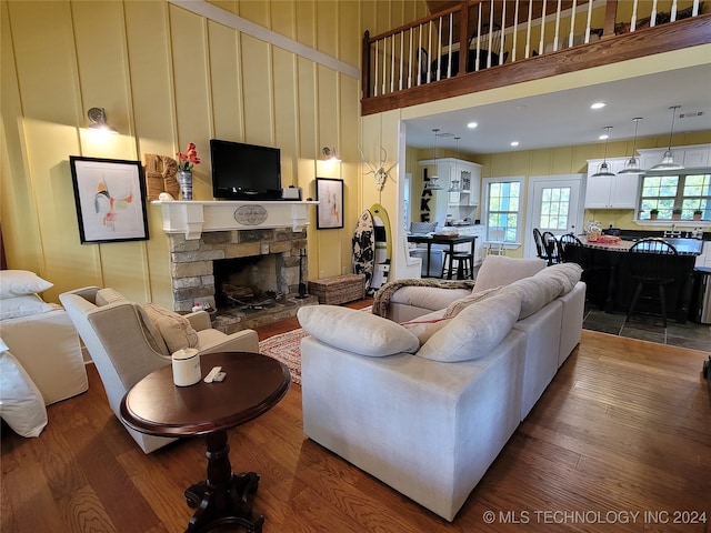 living room featuring a towering ceiling, hardwood / wood-style floors, and a stone fireplace