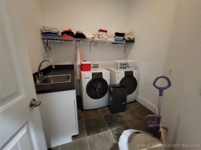 laundry area featuring washer and clothes dryer, dark tile patterned flooring, and sink