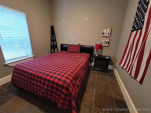 bedroom with dark tile patterned floors and multiple windows