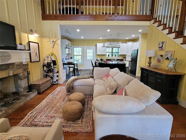 living room with a stone fireplace, a towering ceiling, and dark hardwood / wood-style floors