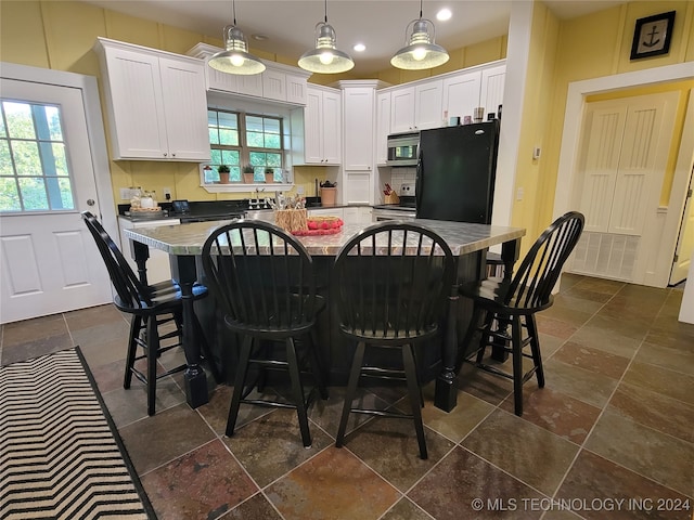 kitchen with white cabinets, a breakfast bar area, decorative light fixtures, and appliances with stainless steel finishes