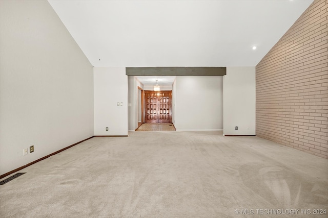 unfurnished living room featuring light carpet, brick wall, and vaulted ceiling