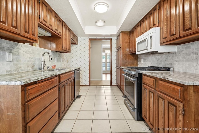 kitchen featuring sink, light stone counters, decorative backsplash, light tile patterned floors, and appliances with stainless steel finishes