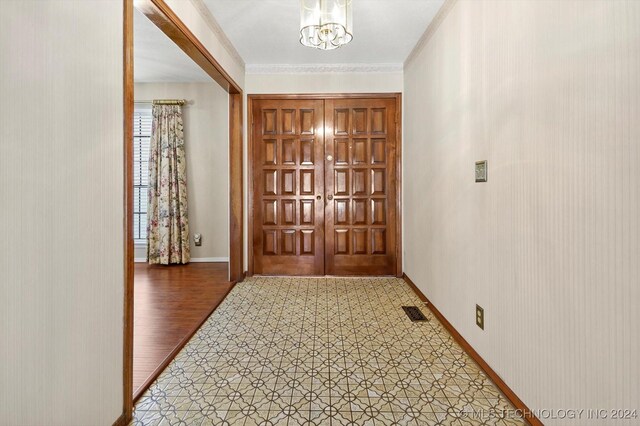 entryway featuring wood-type flooring, an inviting chandelier, and crown molding