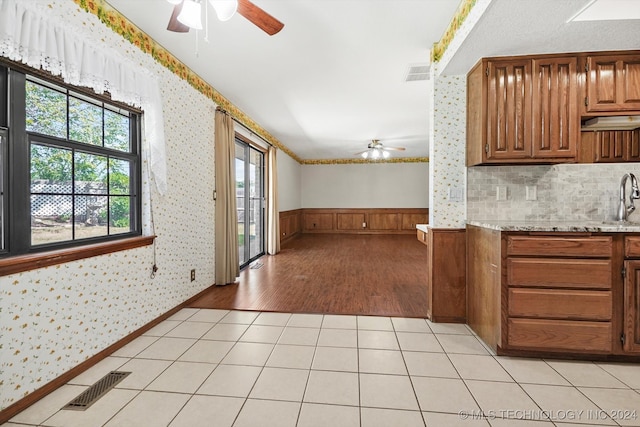 kitchen with backsplash, wood walls, sink, and light hardwood / wood-style floors