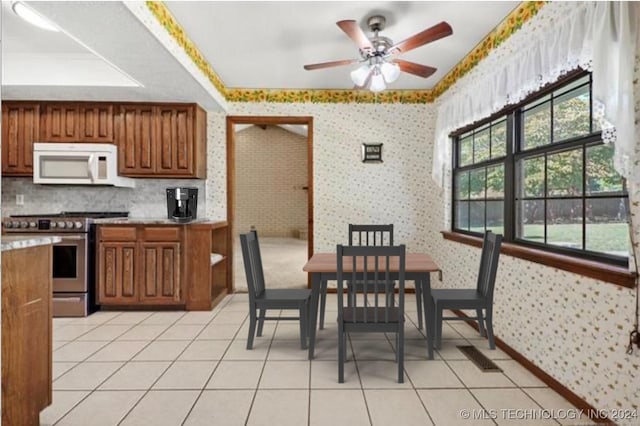 kitchen featuring stainless steel range, light tile patterned floors, and ceiling fan