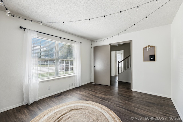 empty room with a textured ceiling and dark wood-type flooring