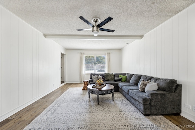 living room featuring a textured ceiling, wooden walls, hardwood / wood-style floors, and ceiling fan