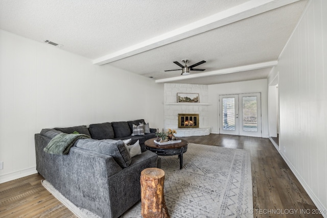 living room with beam ceiling, dark hardwood / wood-style floors, and a stone fireplace