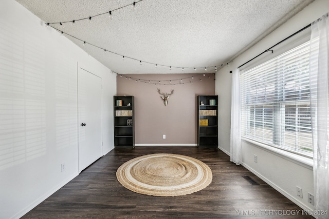 unfurnished room featuring a textured ceiling and dark wood-type flooring