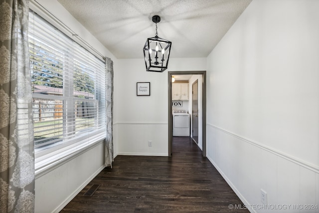 hall with a textured ceiling, dark hardwood / wood-style floors, washer / dryer, and a notable chandelier