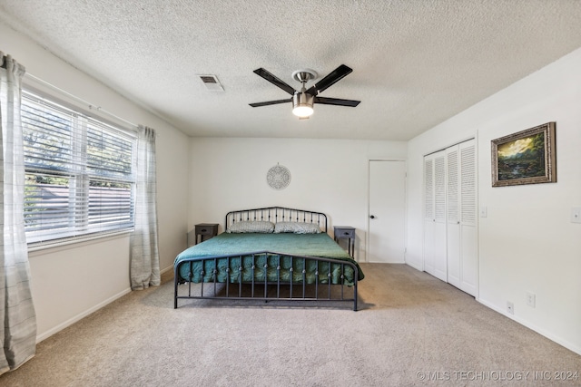 carpeted bedroom featuring ceiling fan, a textured ceiling, and a closet