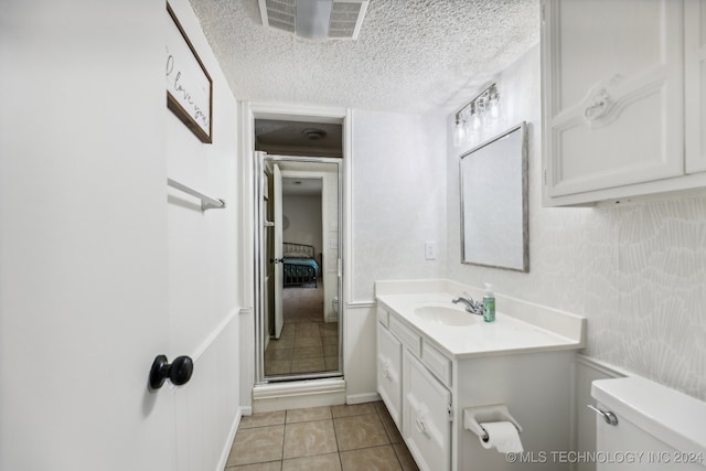 bathroom with vanity, a textured ceiling, tile patterned floors, toilet, and a shower with door