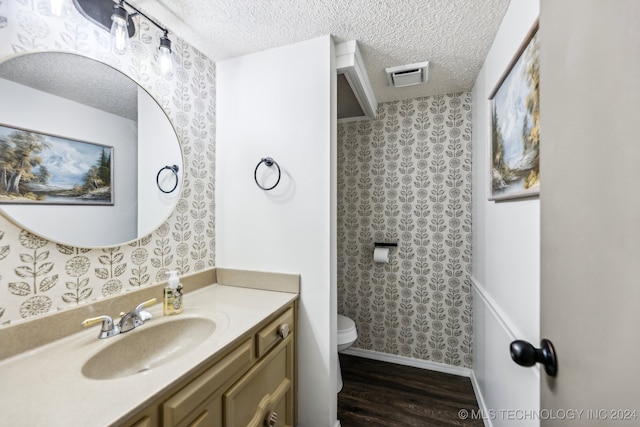 bathroom featuring a textured ceiling, wood-type flooring, vanity, and toilet